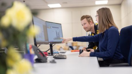 Frau zeigt Mann etwas auf einem Computerbildschirm, Büro