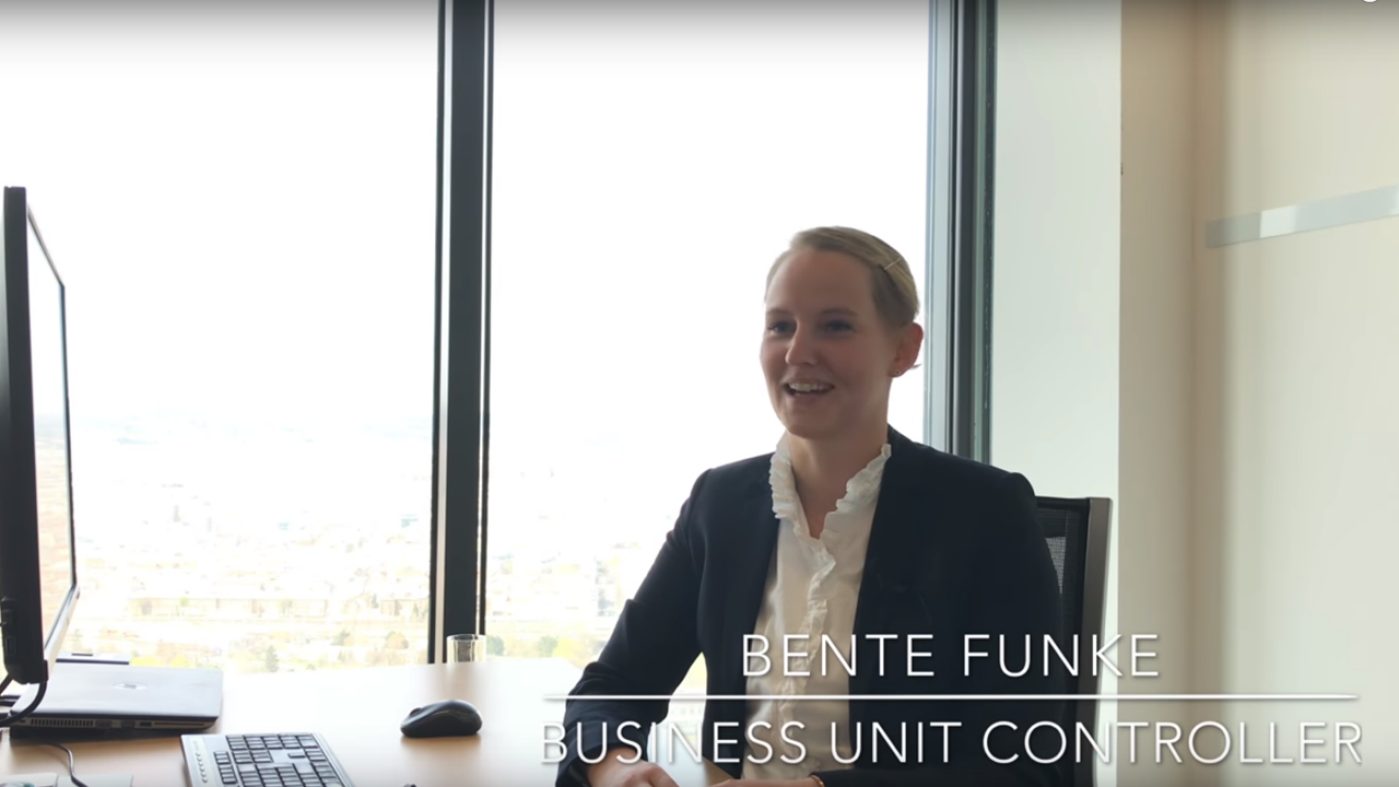 woman in black blazer in an office, desk, talking