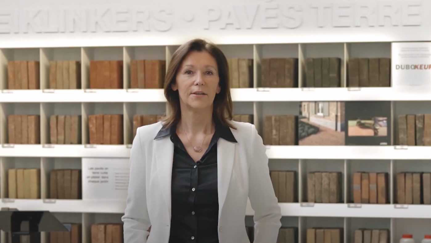woman in a white blazer n front of exhibition wall