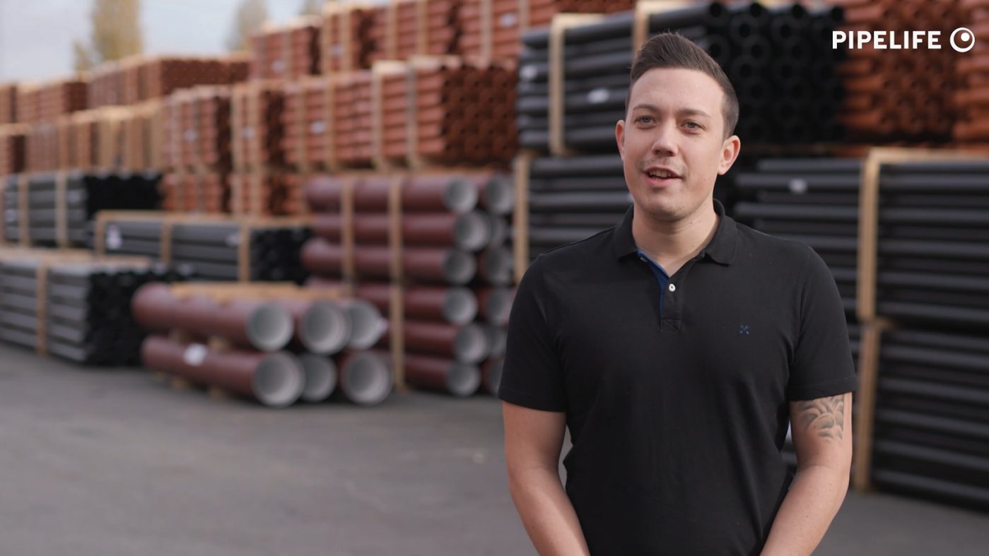 Man in black T-shirt at a storage place for plastic pipes