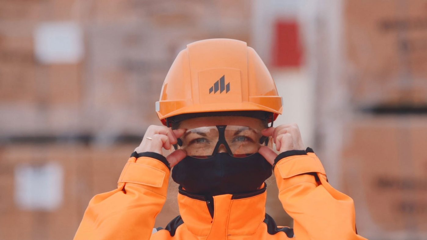 Woman with protective clothing puts on goggles